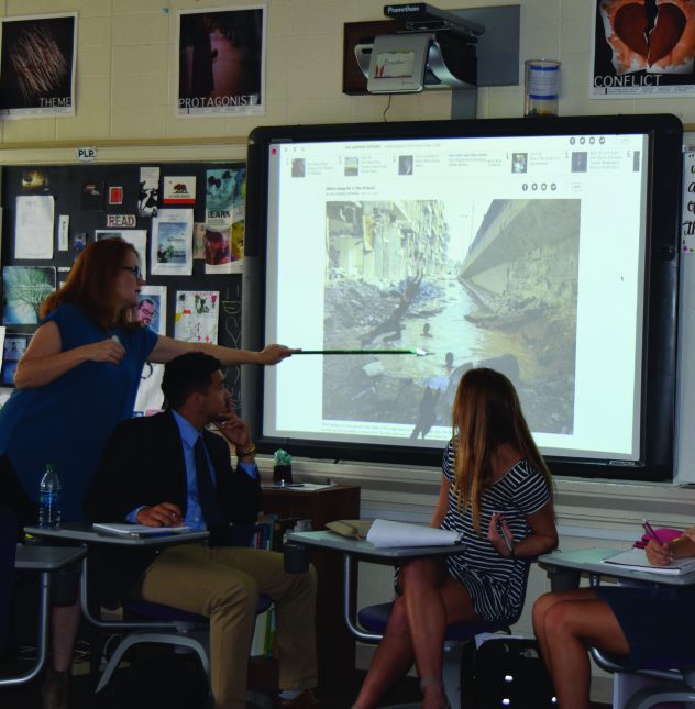 Ms. Forster points to the photo displayed on the board, to help her students analyze the context of the photo. Photo by Marley Orange.