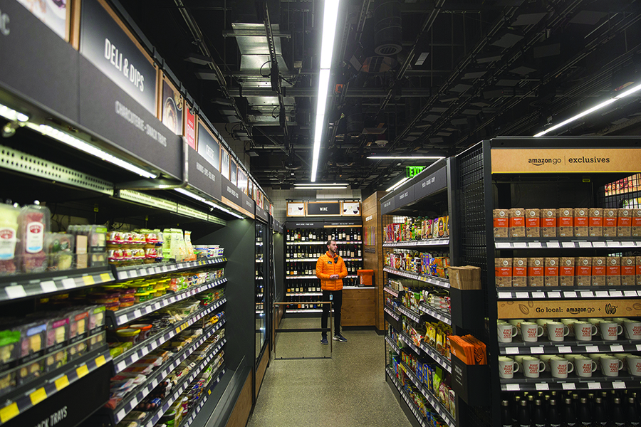 An employee stands at the Amazon Go store in Seattle, Washington, U.S., on Wednesday, Jan. 17, 2018. After more than a year of testing with an employee-only focus group, Amazon Go opens to the public Monday in downtown Seattle, putting to the test the online retailers technology that lets shoppers grab what they want and leave without paying a cashier. Photographer: Mike Kane/Bloomberg via Getty Images
