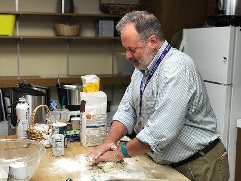 Dr. Charlie Scott, Upper School English Teacher, presses two pieces of dough together in preparing biscuits.