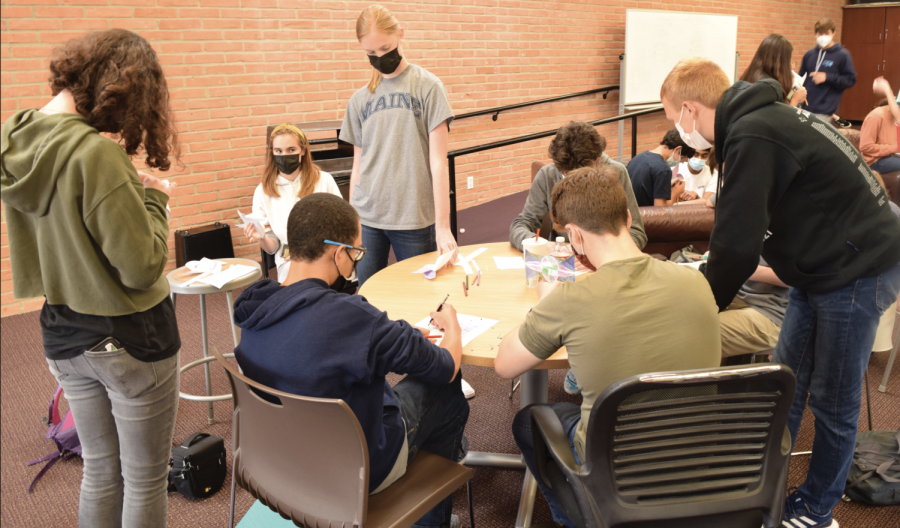 Students sit at tables and work on their pinwheels together.
