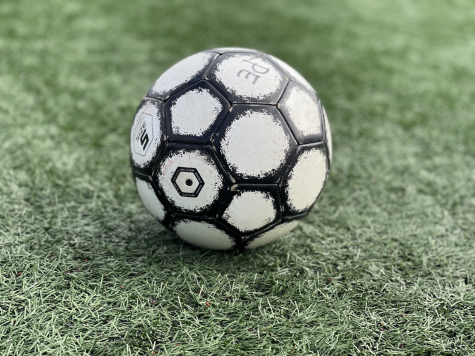A soccer ball rests in the middle of a field. 