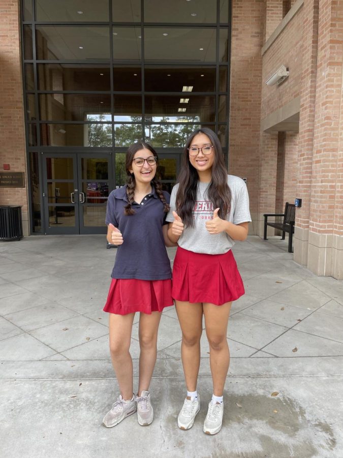 Seniors Mia Price and Sarah Xu give a thumbs-up to the camera by the school entrance on Mock the Mavs day.