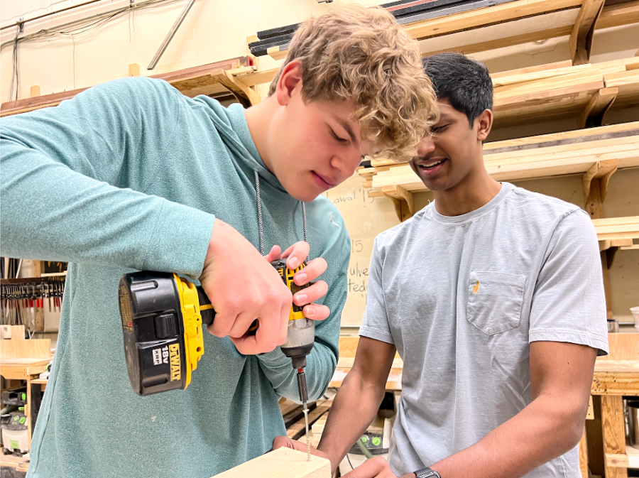 Junior Rohan Yalamanchili helps keep a wooden board steady as junior Mason Howes drills a screw into a wooden board to make a box. On the second day of the "Fixer Upper" class, students learned the usefulness of various tools.