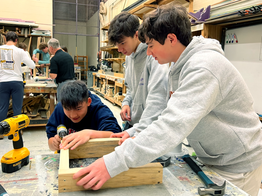 Juniors Tyler Karkowsky and Grant Smith hold onto wooden boards to ensure a stable foundation for sophomore Gabe Xu to drill a screw into the side. 