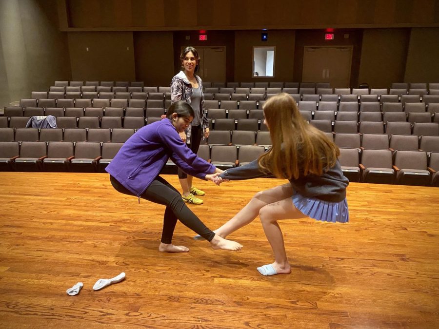 Freshmen Anna Busa and Unaisah Saeed strengthen their balance skills by using particular partner activities in their "Inspired Choreography" Interim Term class. Their teacher, Ms. Anjaly Thakker, who teaches math in the Upper School, watched their teamwork to lower to the ground and back up again without falling over.  