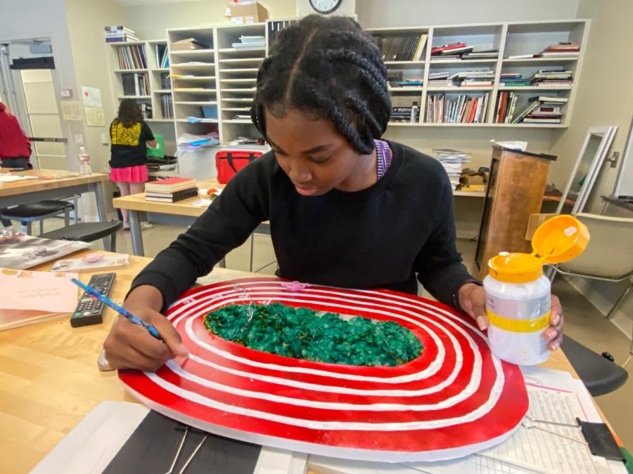 London Norris, a junior,  paints a canvas on which she painted circular stripes to represent the lanes on a track. 