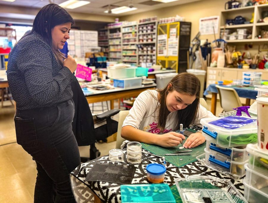 Art assistant Ms. Lauren Quiroga tells Audrey Brown, a junior, how to set crystals into silver clay. “I have never done this before and Mrs. Q was super thorough and patient when explaining it to me," Brown said.