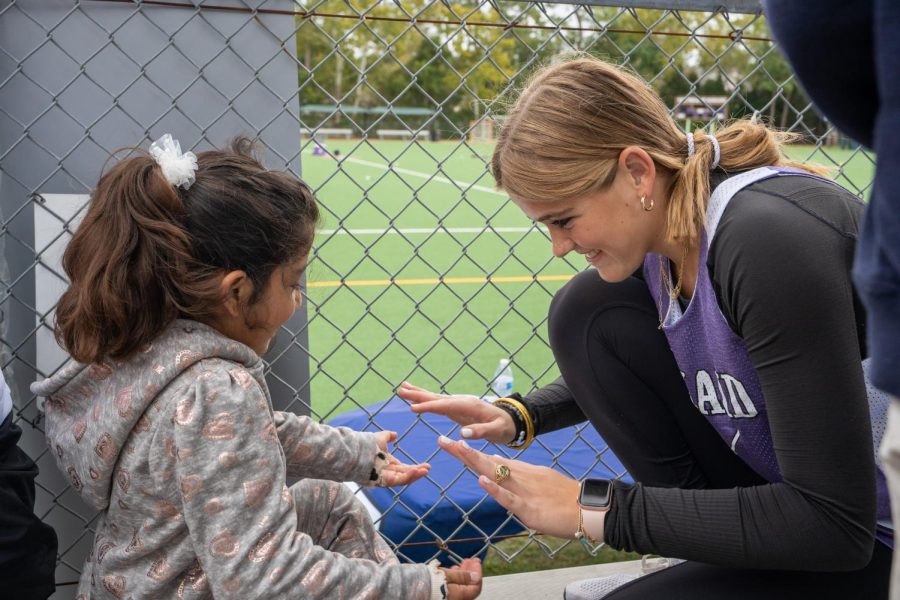 Freshman Lindsey Morgan high fives a young Afghan refugee student. She helped teach field hockey to a group of refugee students. 