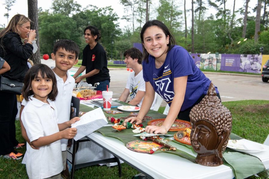 Freshman Ayla Patel smiles; she talks to Lower School students about the Sri Lanka booth.