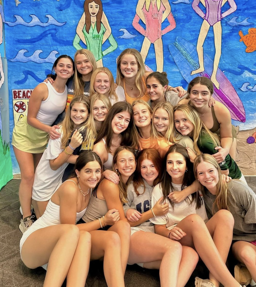 SOK Club members pose by a wall in the student commons, decorated for the week of celebrations. The student commons is adorned with drawings and artwork depicting the various varsity sports teams on campus.