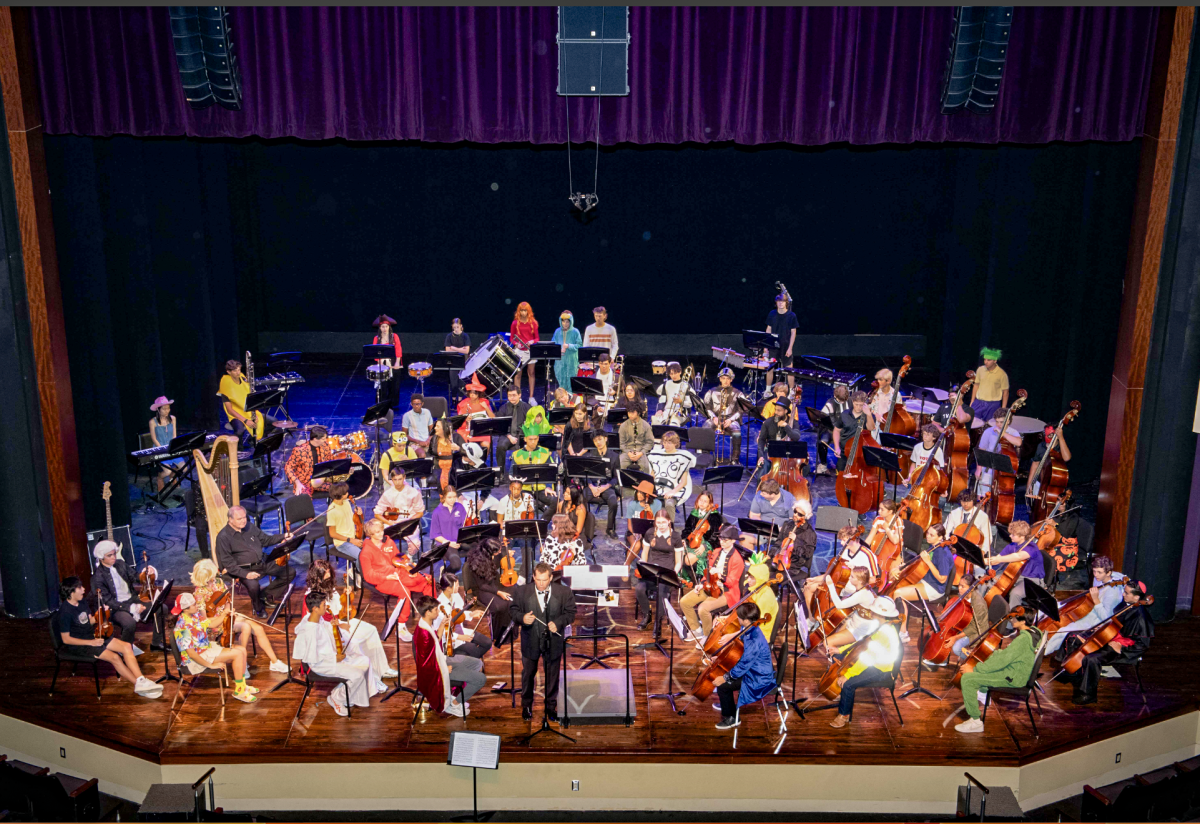 The+orchestra+and+band+after+playing+their+symphony+pieces+in+their+costumes.+Mr.+Kastner%2C+Orchestra+director%2C+is+standing+on+the+center+of+the+stage.