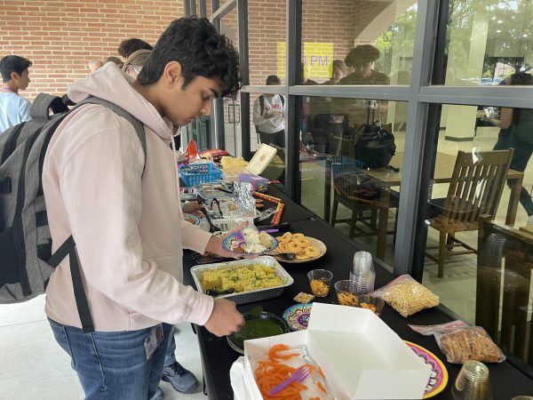 Senior Kaveen Shah tries mint chutney, a tangy sauce usually eaten as a side with appetizers.