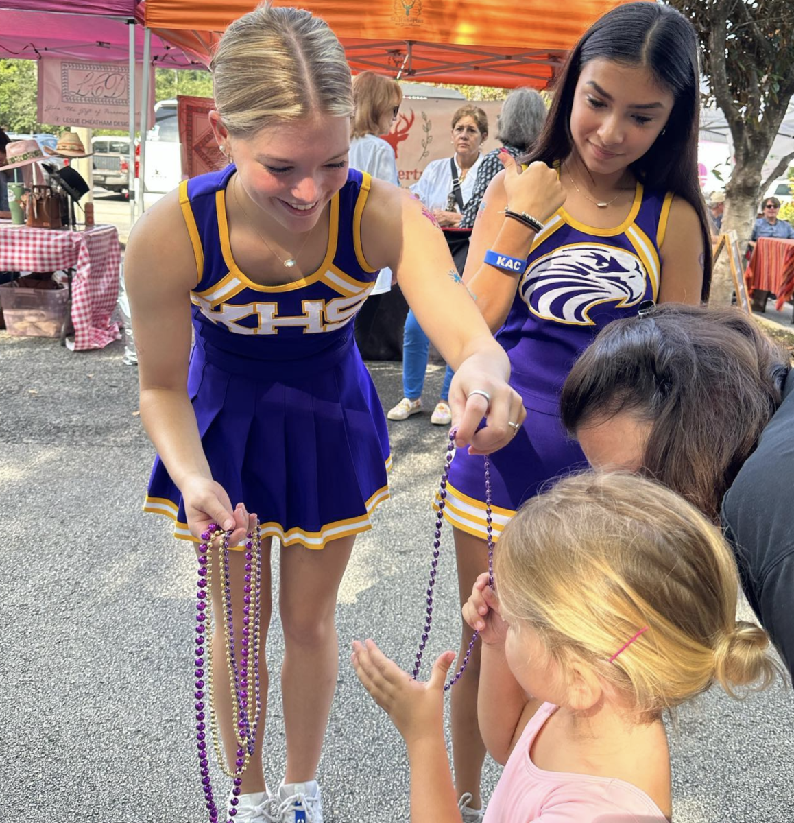 Cheerleaders hand out beads at Sterling Market.