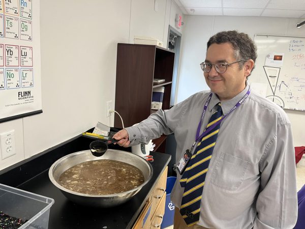 Upper School science teacher Dr. Adam Capitano poses with a bowl of dirty water before purifying it.
