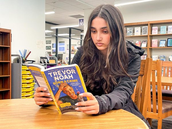 Freshman Sophie Lighvani reads her English assigned reading, Born a Crime by Trevor Noah, in the library. I love the library because of its helpful resources and spacious studying areas,” Lighvani said.