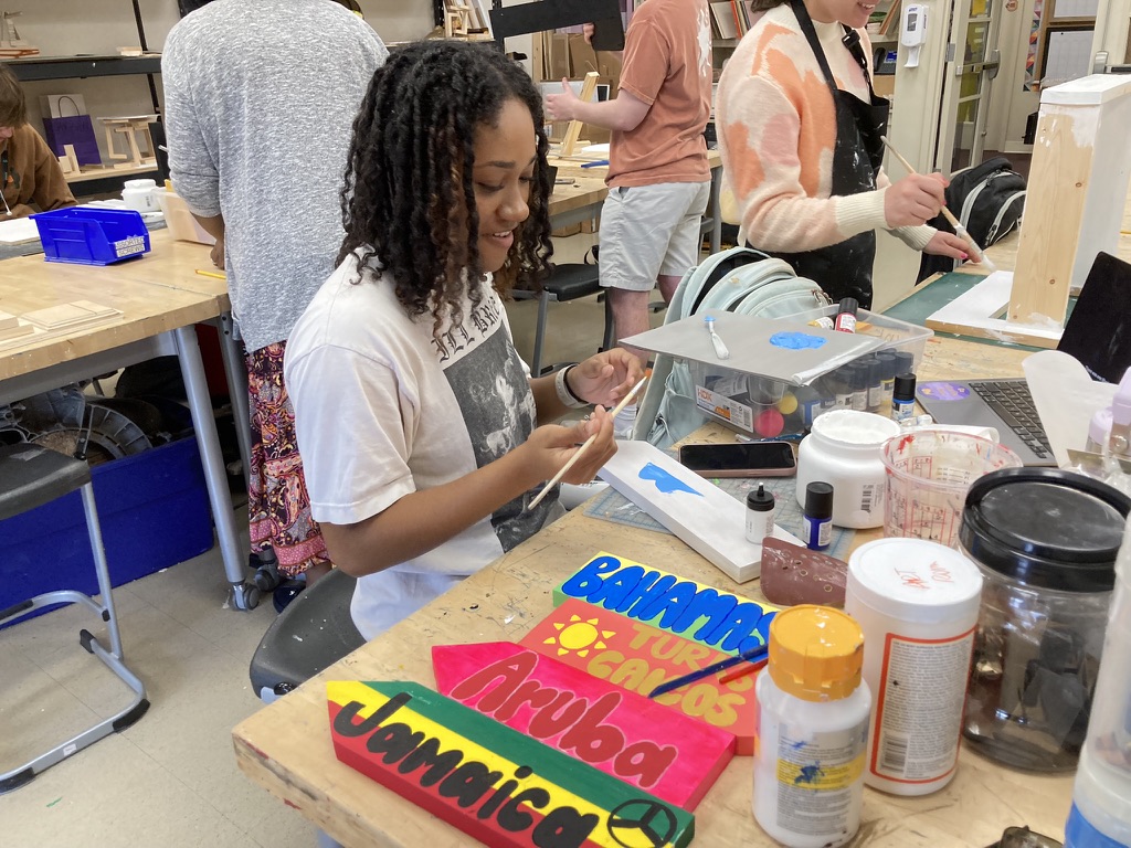 Senior Rayya James paints boards to put on her tensegrity table project in her advanced sculpture class. She is preparing the pieces to put together into the final product.