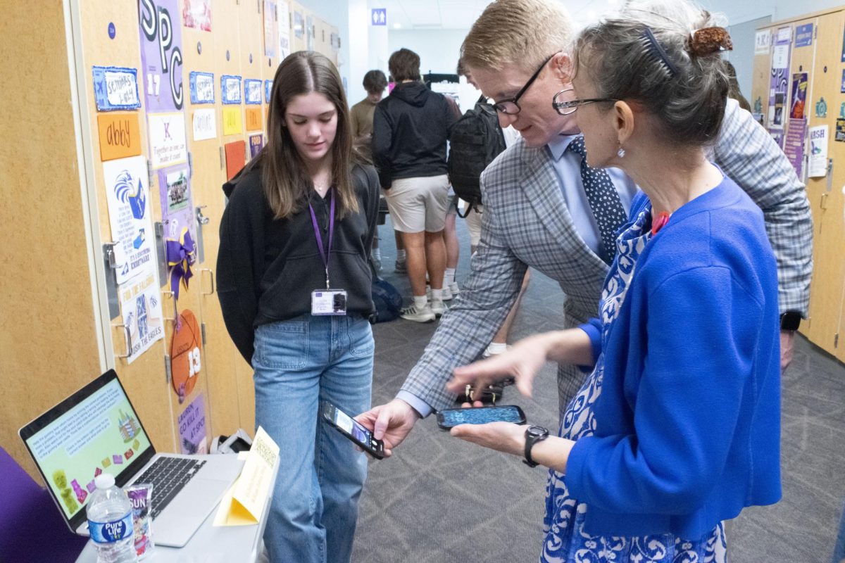 Mr. Josh Ramey, dean of students, scans a QR code on freshman Evie Kinsey's geometry expo project, as learning specialist Ms. Laurie Anderson watches.