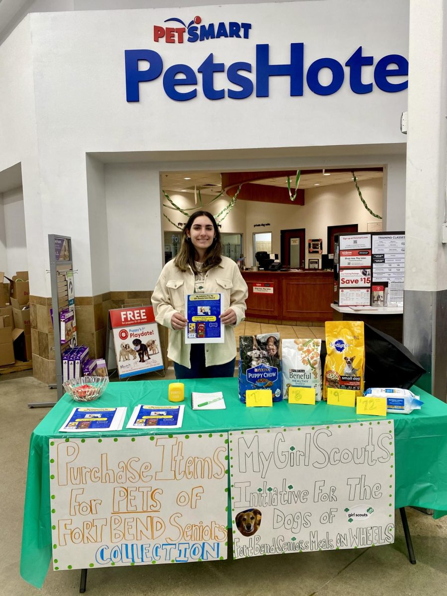 Senior Sabrina Nader poses in front of her booth at Fort Bend Senior Center selling dog supplies as part of her Girl Scout Gold Award project.