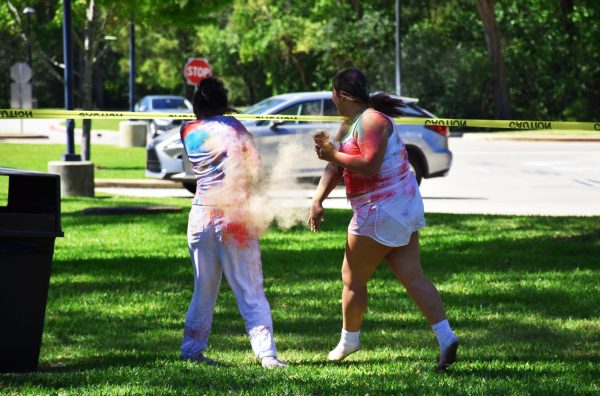 Freshman Zora Watts and Phoebe Ostrosky throw vibrant powder during the annual Holi celebration. “I can celebrate other people's cultures and be able to experience the joy they get from it,” Ostrosky said. 