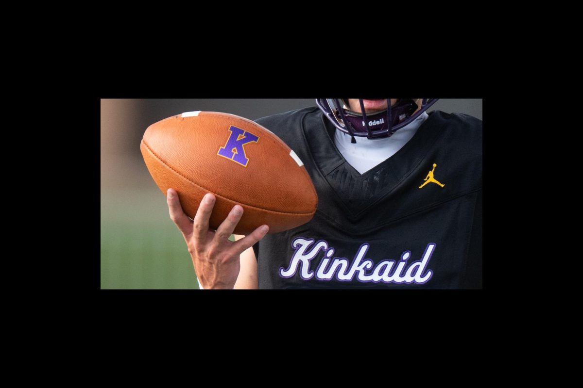 A Kinkaid varsity football player holds up a football featuring the school’s purple Kinkaid logo. The varsity team is preparing for its upcoming matchup against Parish Episcopal.